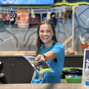 Elevate Mesa employee smiling and handing jump socks out. Image is the tile for sensory Sundays Discount at Elevate