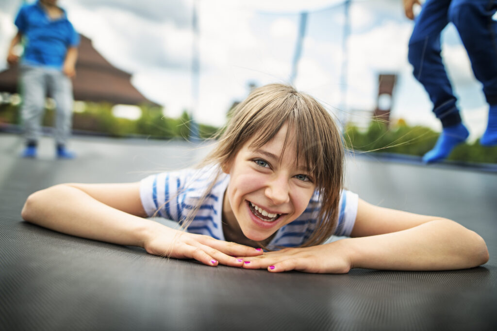 Happy Little boys aged 6 and the girl aged 10 having fun on trampoline.